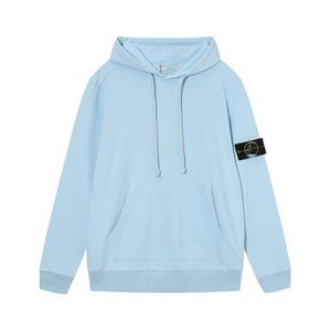 May include: A light blue hoodie with a front pocket and a drawstring hood. The long-sleeved sweatshirt features a small black and gold patch on the left sleeve. The garment is made of a soft material.