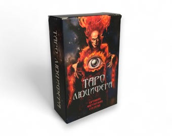 May include: A rectangular deck of cards box featuring a dark, cosmic background with a central figure surrounded by orange and red flames. The figure has a large, realistic eye on its chest. The text reads "ТАРО ЛЮЦИФЕРА" and "ДРЕВНЯЯ МАГИЧЕСКАЯ СИСТЕМА".