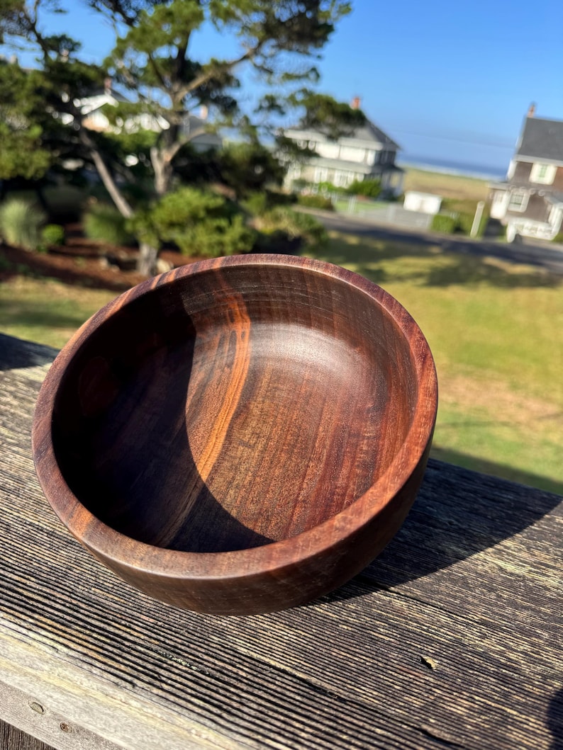 Pu&ograve; includere: Una ciotola di legno fatta a mano, di colore marrone scuro con venature del legno visibili. La ciotola ha un interno liscio e lucido e un bordo leggermente angolato. Questa ciotola decorativa &egrave; perfetta per servire o esporre.