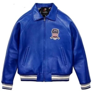 Op de afbeelding: Een helderblauwe leren jas met een klassieke kraag en een ritssluiting. De jas heeft een patch op de borst met een patriottisch ontwerp en wit en blauw gestreepte manchetten en zoom. Een stijlvol bovenkledingstuk.