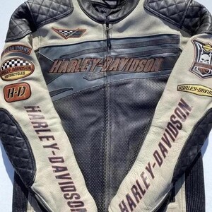 以下が含まれることがあります： 黒とクリーム色のハーレーダビッドソンモーターサイクルジャケット。ジャケットは胸と袖にハーレーダビッドソンのロゴが入っています。袖にはキルティングのディテールとパッチが付いています。ジャケットはジッパー開閉で、スタンドカラーです。