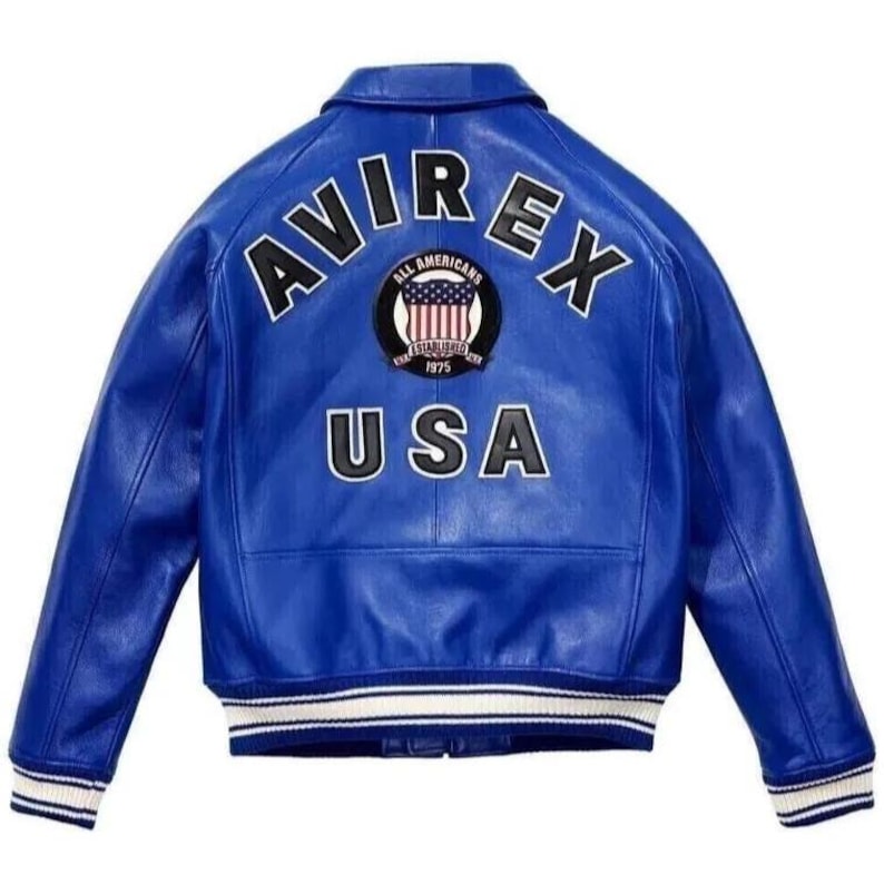 Op de afbeelding: Een felblauwe leren jas met het woord "AVIREX" in witte blokletters over de bovenrug. Het woord "USA" staat ook in het wit. Een cirkelvormige patch met een ontwerp van de Amerikaanse vlag staat tussen de woorden.