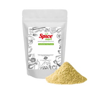 May include: A white packet of asafoetida hing powder with a pile of the powder in front of it. The packet has a label with the text "Spice mart" and "Asafoetida Hing Powder". The background is white.