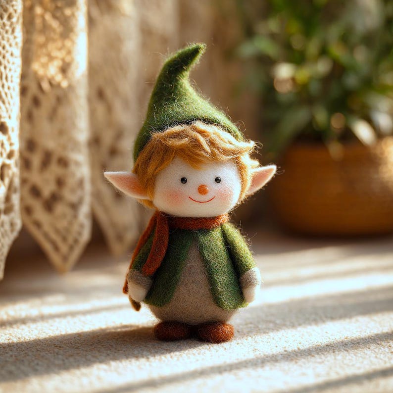 May include: A handcrafted felt elf doll with a green hat and jacket, a red scarf, and orange hair. The doll has a white face with a small orange nose and a smiling mouth. The elf is standing on a light-colored surface.