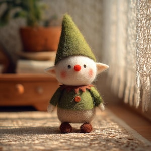 May include: A handmade felt elf doll with a green pointed hat and matching green sweater. The doll has a white face with rosy cheeks, a red nose, and small brown feet. The elf is standing on a patterned surface.