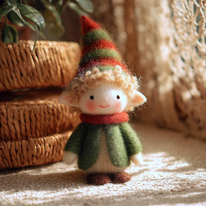 May include: A handmade felt doll of an elf with a red and green striped hat, curly blonde hair, and a red scarf. The elf wears a green jacket and brown shoes. The doll has a smiling face with rosy cheeks and small black eyes.