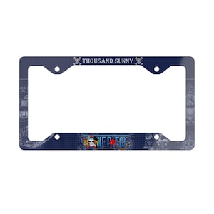May include: A navy blue license plate frame with the words "THOUSAND SUNNY" and "ONE PIECE" printed on it. The frame has a detailed nautical map design and skull and crossbones graphics.
