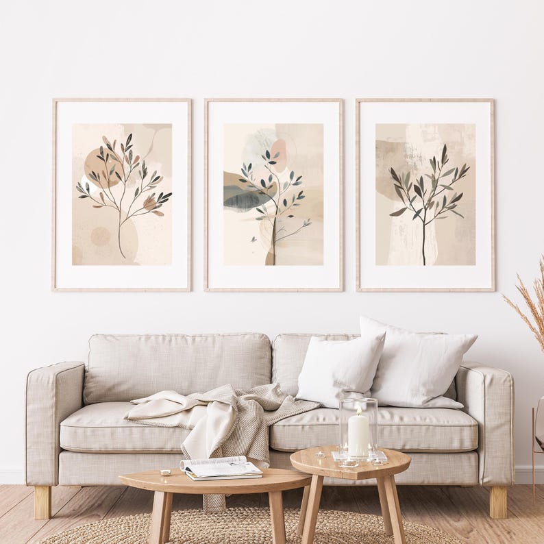 May include: Three framed abstract art prints with botanical designs. Each print features a stylized tree with leaves against a neutral background with soft colour blocks in beige, brown, and muted tones. The frames are light wood.