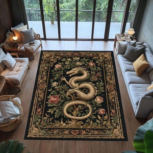 May include: A rectangular black area rug with a detailed design featuring a golden dragon, pink roses, and green foliage. The rug has a decorative border and is placed in a living room setting with natural light.