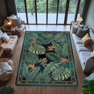 Op de afbeelding: Een rechthoekig vloerkleed met een tropisch bladerpatroon. Het kleed toont grote groene bladeren, waaronder monstera en palmbladeren, tegen een donkerblauwe achtergrond. Oranje paradijsvogelbloemen zijn verspreid. Het kleed heeft een gouden rand.