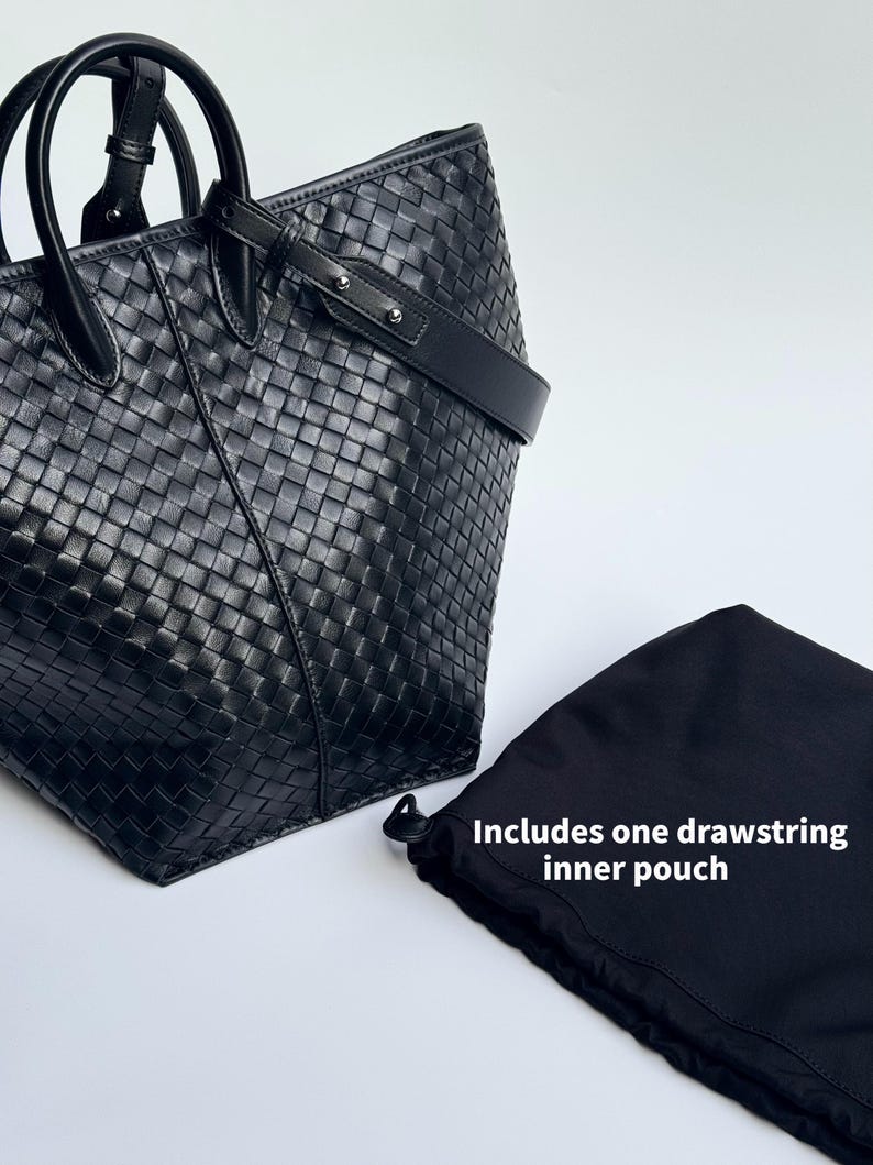May include: Black leather tote bag with a woven design, featuring a top handle and a shoulder strap. Includes a black drawstring inner pouch. The bag is set against a white background.