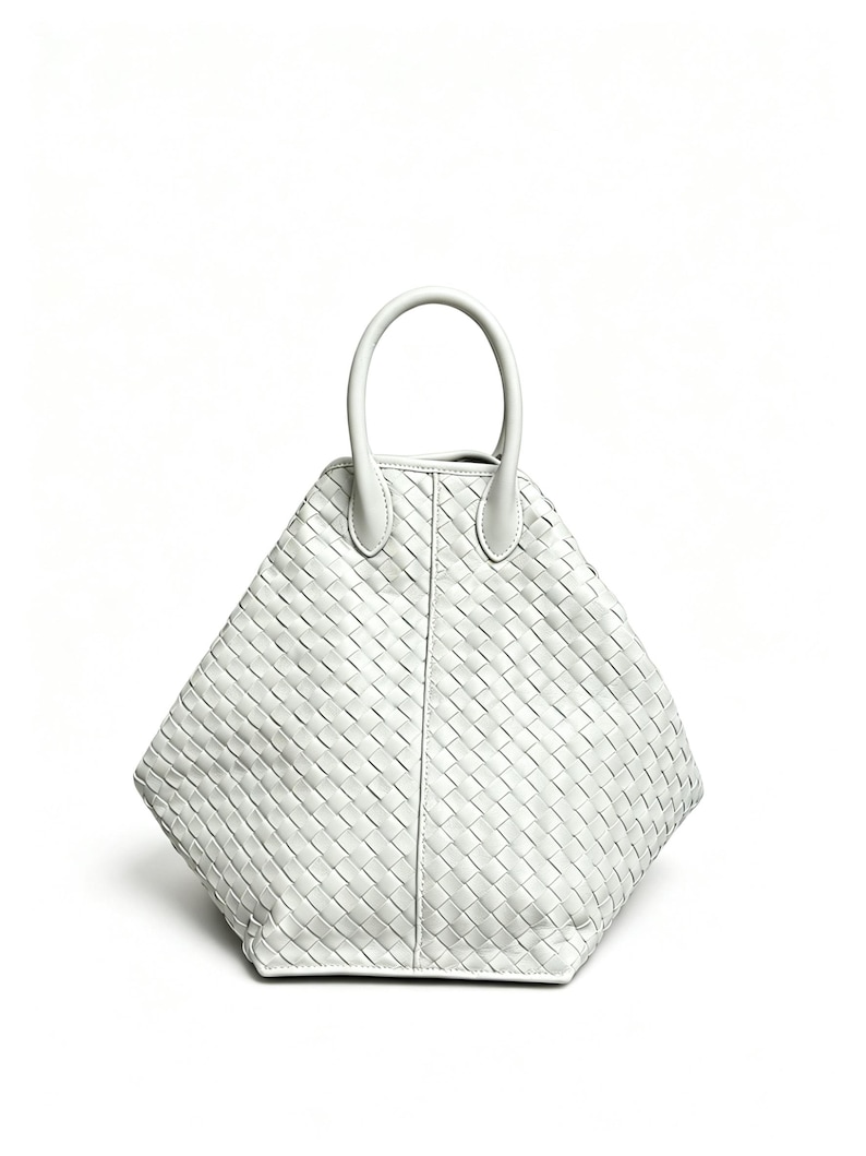 May include: A white, diamond-shaped handbag with a woven pattern. The bag features a single, rounded handle and a structured design. The material appears to be leather or a similar material. The bag is set against a plain white background.