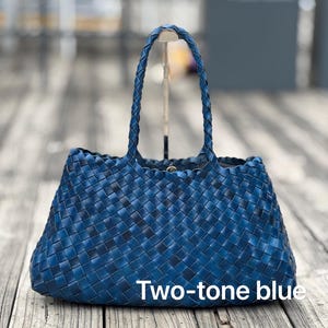 May include: A two-tone blue woven tote bag with braided handles. The bag has a rectangular shape and a woven pattern. The text "Two-tone blue" is displayed on the front of the bag.
