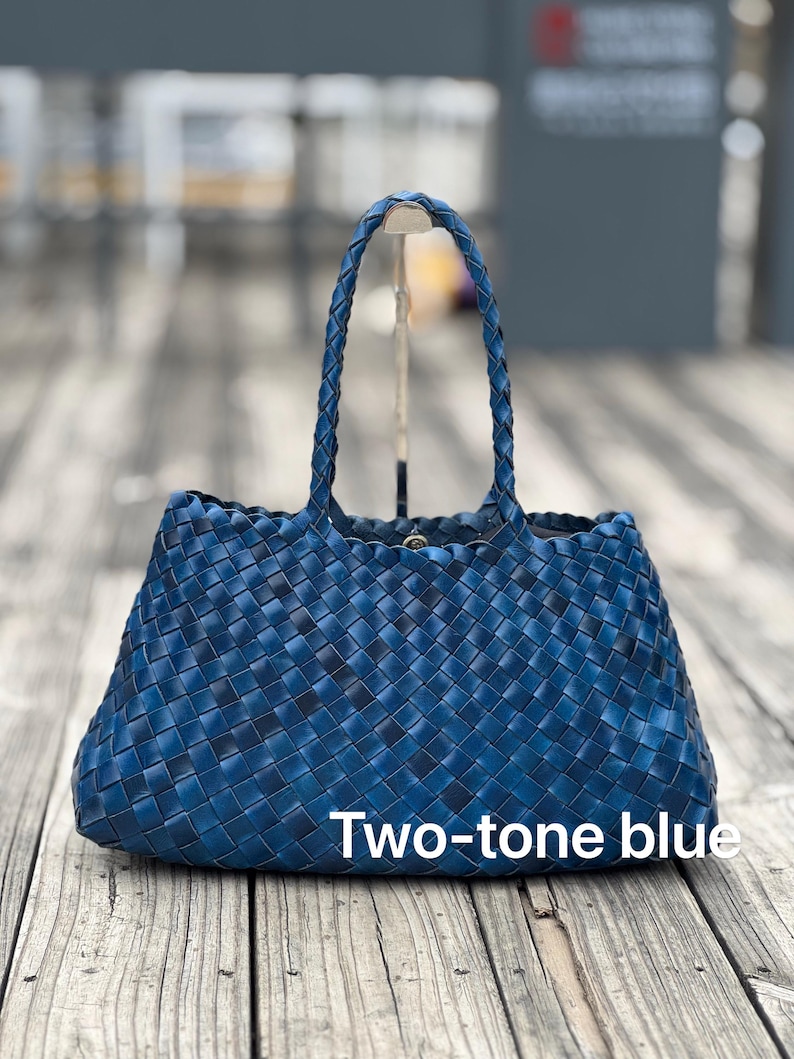 May include: A two-tone blue woven tote bag with braided handles. The bag has a rectangular shape and a woven pattern. The text "Two-tone blue" is displayed on the front of the bag.
