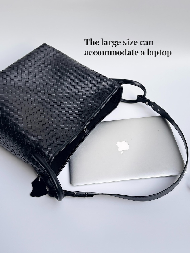 May include: Black woven leather tote bag with a long shoulder strap. The bag is open, revealing a silver laptop inside. The text on the image reads: "The large size can accommodate a laptop."