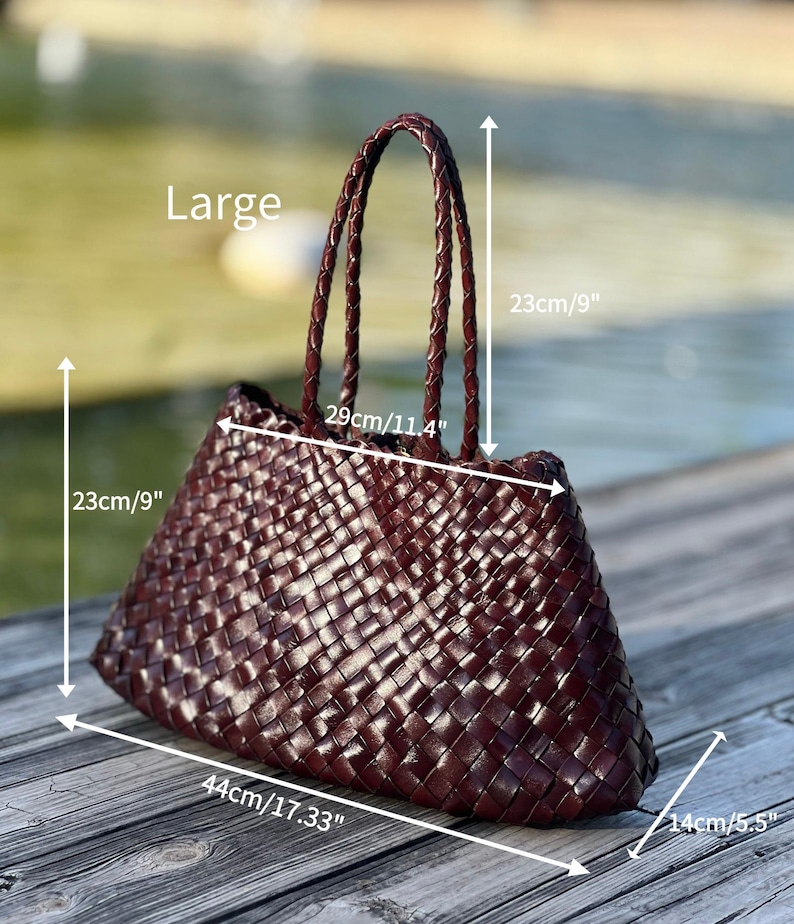 May include: A large, woven burgundy tote bag with braided handles. The bag measures 17.33 inches wide, 9 inches high, and 5.5 inches deep. The handles are 11.4 inches long. The bag is displayed outdoors.