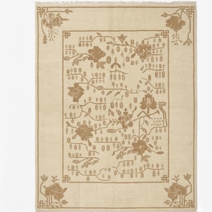 May include: Cream-coloured rectangular rug with a floral pattern in brown tones. The rug has a border and corner details with stylised flowers and foliage. The central design features flowers, branches, and small leaf-like shapes.