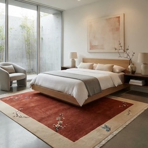 May include: A rectangular area rug featuring a deep rust-red center field with a wide beige border. The rug is decorated with embroidered floral branches and a blue butterfly motif, finished with short white fringe along the shorter edges.