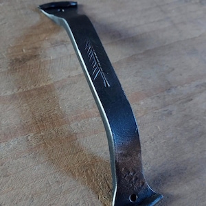 Peut inclure: Une poignée en métal noir forgée à la main, de forme incurvée. La poignée présente une gravure décorative en forme de plume et un trou à une extrémité. Pour un meuble.