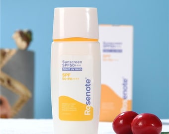 May include: A white sunscreen bottle with a white cap and yellow label. The label reads "Sunscreen SPF50+++ FIGHT UV RAYS" and "SPF 50+PA++++". The brand name "Rosenote" is printed on the bottle. Two red, round objects are in the foreground.