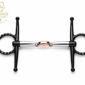 Può includere: Un filetto ad aste per cavalli con anelli e aste laterali neri con accenti color argento. L'imboccatura è composta da due segmenti metallici color argento collegati da un anello centrale ovale color rame. Logo Prestige Horse Gear visibile.