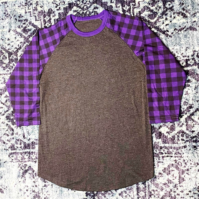 Purple Buffalo Plaid Sleeve 3/4 Raglan Shirt with Dark Heather Grey/Gray Body. Shirt has a longer length and rounded hem