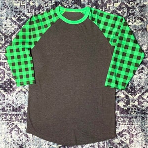 Green Buffalo Plaid Sleeve 3/4 Raglan Shirt with Dark Heather Grey/Gray Body. Shirt has a longer length and rounded hem