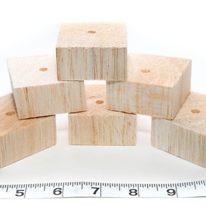 May include: Six unfinished wooden blocks stacked in a pyramid shape. Each block has a small hole drilled in the center of the top surface.