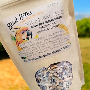 May include: A brown paper bag with a clear window showing a mix of grains and legumes. The bag is labeled "Bird Bites Freeze Dried Diets Whole Balance Cooked & Freeze Dried Ready-to-Eat Grains & Legumes". The label also lists the ingredients, which are all organic or non-GMO, minimally processed. The bag is labeled "No Cooking - No Soaking - No Corn - No Peanuts - No Fillers".