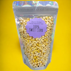 May include: A clear plastic bag filled with freeze-dried sweet corn kernels. The bag has a purple label that says "Bird Bites Healthy Freeze Dried Treats 100% Sweet Corn".