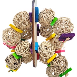 May include: A wooden bird toy with multiple woven straw balls and colorful wooden blocks. The toy is designed to hang from a ceiling or perch.