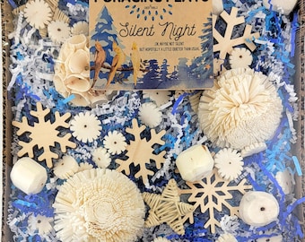 May include: A box filled with a variety of wooden and paper foraging toys for small animals. The toys are in shades of white and natural wood. The box is filled with blue and white shredded paper. The box has a card on top that says "Foraging Flats Silent Night OK maybe not silent but hopefully a little quieter than usual."