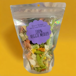 May include: A clear plastic bag filled with a variety of freeze-dried vegetables. The bag has a purple label that says "Bird Bites Healthy Freeze Dried Treats 100% Veggie Medley".