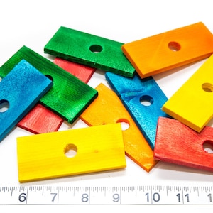 May include: A set of nine wooden blocks, each painted a different color: blue, green, yellow, orange, and red. Each block has a hole in the center.