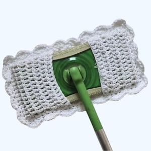 Puede incluir: Una funda blanca de cabezal de fregona, de ganchillo, con un borde festoneado, que cubre un cabezal de fregona verde y blanco. El mango de la fregona es verde y plateado. La imagen es un primer plano del cabezal de la fregona.