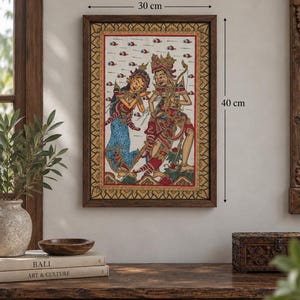 Op de afbeelding: Een ingelijst rechthoekig schilderij met twee figuren in versierde kleding, een blauw en rood kleurenpalet en een crèmekleurige achtergrond met kleine rode motieven. De lijst meet 30 cm in de breedte en 40 cm in de hoogte, zoals aangegeven.