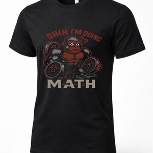 May include: Black t-shirt featuring a cartoon gorilla lifting weights. The gorilla is red and gray, with the text "SHHH I'M DOING ?? MATH" in red and gray. The weights have the numbers 25, 35, and 45 on them. A humorous design for fitness enthusiasts.