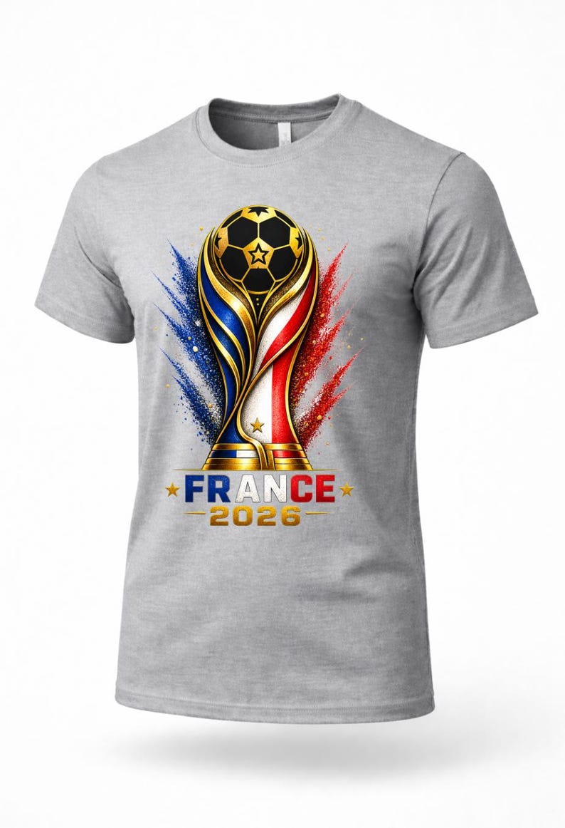 May include: Gray t-shirt featuring a soccer trophy design with a soccer ball, and the text "FRANCE 2026". The trophy design incorporates the colors of the French flag, with blue, white, and red accents.