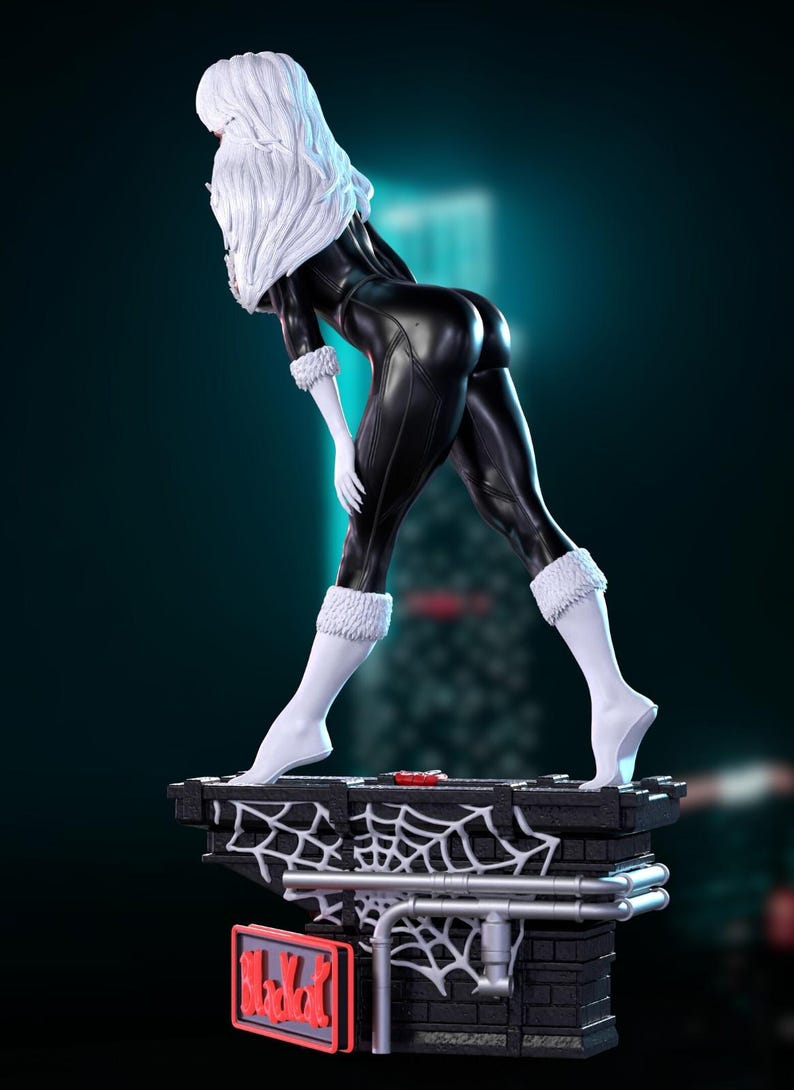May include: A statue of a character in a black catsuit with white fur trim and white hair. The figure is posed on a brick-like base with a spiderweb design. The statue has a dynamic pose and is set against a dark background.