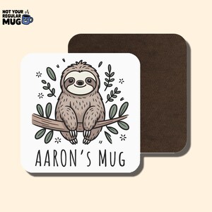 K&ouml;nnte beinhalten: Quadratischer wei&szlig;er Untersetzer mit einem Cartoon-Faultier, das auf einem Ast sitzt, umgeben von Bl&auml;ttern und Blumen. Der Text "AARON'S MUG" ist darunter gedruckt. Ein brauner Untersetzer befindet sich dahinter. Oben links steht "NOT YOUR REGULAR MUG".