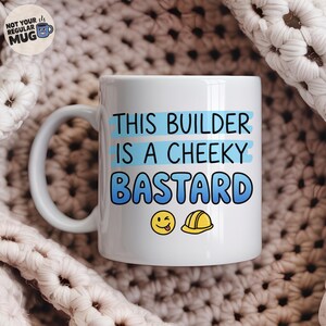 Op de afbeelding: Een witte keramische mok met de tekst THIS BUILDER IS A CHEEKY BASTARD in blauwe letters met lichtblauwe penseelstreekaccenten. Onder de tekst staan een gele knipogende smiley-emoji en een geel icoon van een veiligheidshelm voor de bouw.