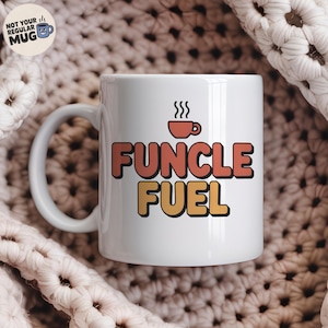 May include: White ceramic mug with the text "FUNCLE FUEL" in orange and yellow block letters, with a small coffee cup graphic above. The mug has a curved handle and a small logo that says "NOT YOUR REGULAR MUG".