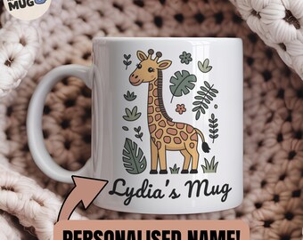 May include: White ceramic mug featuring a giraffe illustration with a brown and tan spotted pattern. The mug has the text "Lydia's Mug" and "Personalised Name!" printed on it. The mug is surrounded by green leaves and flowers.