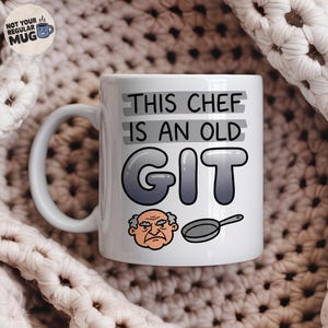 May include: A white ceramic mug featuring the black text THIS CHEF IS AN OLD GIT with a gradient gray bubble font for the word GIT. Below the text is a cartoon illustration of an elderly person with a grumpy expression next to a frying pan.