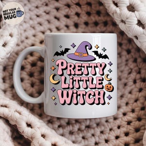 May include: White ceramic mug with the text "Pretty Little Witch" in pink and orange lettering, decorated with a purple witch hat, bats, stars, moons, and a jack-o'-lantern. The mug has a curved handle.