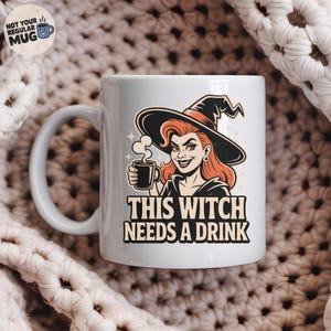 Pode incluir: Caneca de cerâmica branca com um desenho de bruxa de desenho animado. A bruxa tem cabelo ruivo, um chapéu preto e segura uma xícara de café. O texto na caneca diz "THIS WITCH NEEDS A DRINK". A caneca tem uma alça branca.