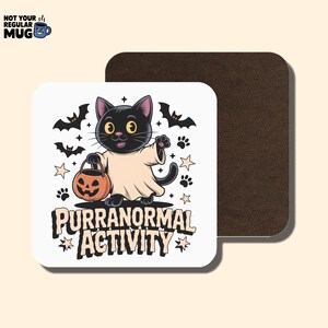 May include: Square white coaster with a black cat dressed as a ghost, holding a jack-o'-lantern. The coaster has the text "PURRANORMAL ACTIVITY" with bats, paw prints, and stars. A brown coaster is behind it.