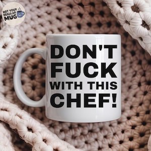 May include: A white ceramic mug featuring the bold black text DON'T FUCK WITH THIS CHEF! printed on the front. The mug has a standard handle and a smooth finish. A small circular logo in the top left corner displays the text NOT YOUR REGULAR MUG.