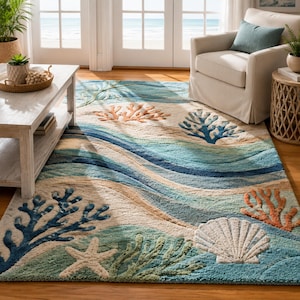 Peut inclure: Un tapis rectangulaire au motif côtier composé de bandes ondulées bleues, turquoise et beiges. Le design présente des motifs texturés en relief de corail bleu foncé et orange, une étoile de mer blanche et un grand coquillage blanc touffeté.