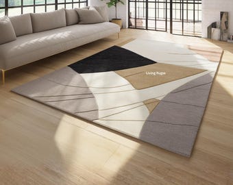 May include: A rectangular area rug featuring an abstract geometric pattern in shades of cream, black, tan, and gray. The design includes bold color-blocked shapes and thin, curved lines. The text Living Rugss is printed on the tan section of the rug.